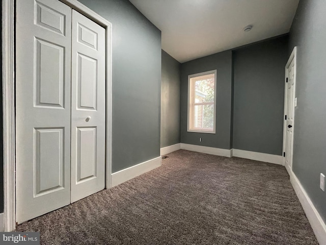 unfurnished bedroom featuring dark carpet and a closet