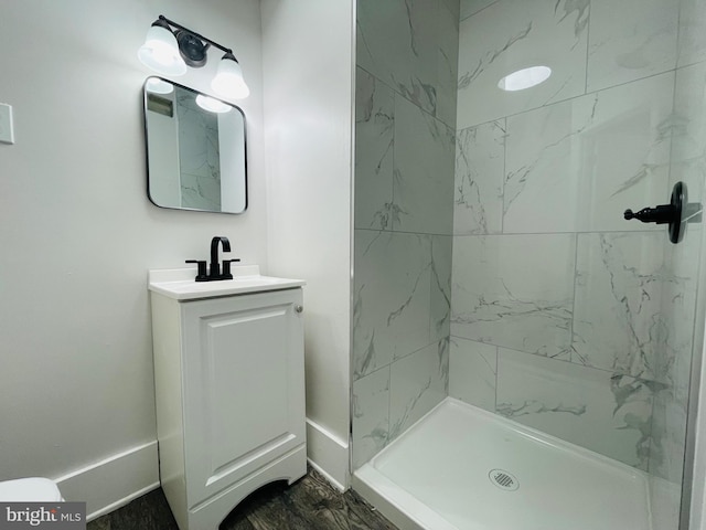 bathroom with vanity, a tile shower, and wood-type flooring