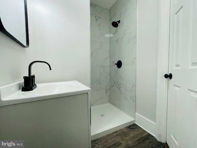 bathroom featuring vanity, wood-type flooring, and tiled shower