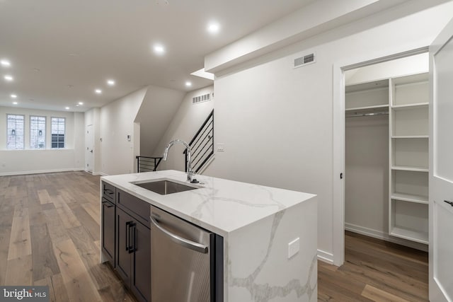 kitchen featuring light stone countertops, stainless steel dishwasher, sink, dark hardwood / wood-style floors, and an island with sink