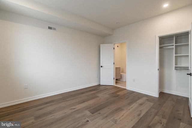 unfurnished bedroom with dark hardwood / wood-style flooring and a closet