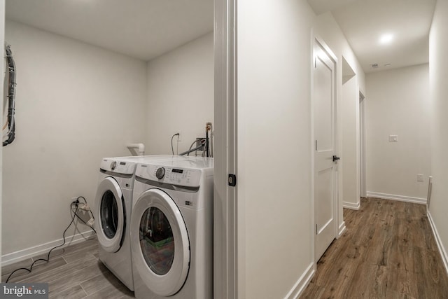 washroom with wood-type flooring and independent washer and dryer