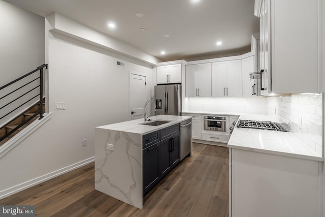 kitchen with white cabinetry, dark wood-type flooring, stainless steel appliances, backsplash, and an island with sink