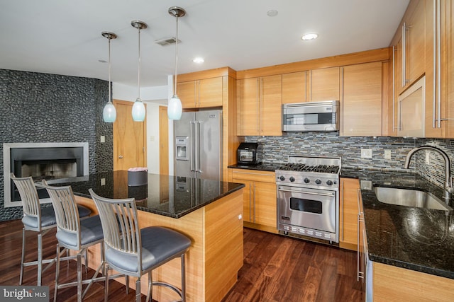 kitchen with dark stone counters, sink, dark hardwood / wood-style floors, premium appliances, and a kitchen island