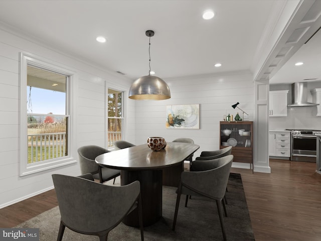 dining room with dark hardwood / wood-style flooring, crown molding, and wooden walls