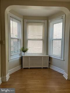 unfurnished dining area featuring radiator, plenty of natural light, and light wood-type flooring