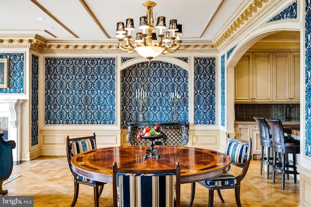 dining space featuring light parquet floors, an inviting chandelier, ornamental molding, and sink