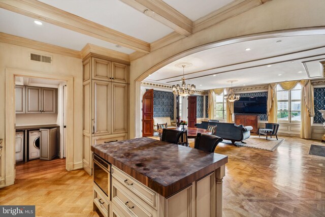 kitchen with light parquet floors, decorative light fixtures, cream cabinetry, butcher block countertops, and a kitchen island