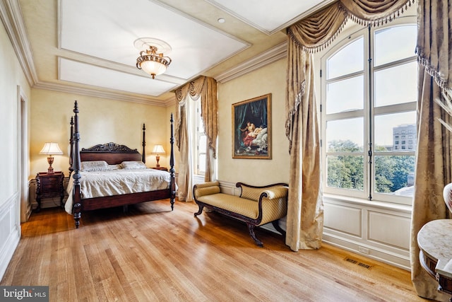 bedroom featuring light hardwood / wood-style floors, crown molding, and multiple windows