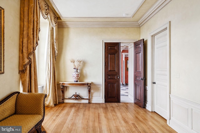 sitting room featuring light wood-type flooring and crown molding