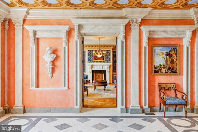 interior space featuring decorative columns, crown molding, and a chandelier