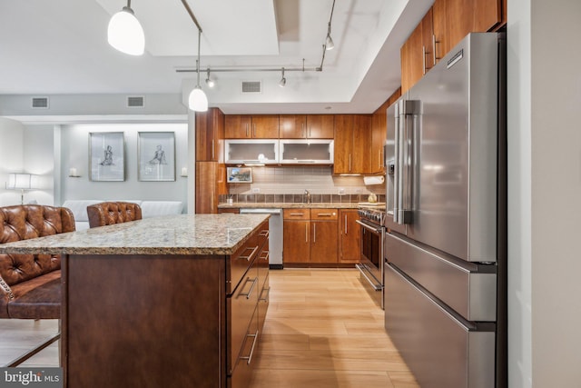 kitchen with a center island, hanging light fixtures, light hardwood / wood-style floors, a breakfast bar area, and high end appliances