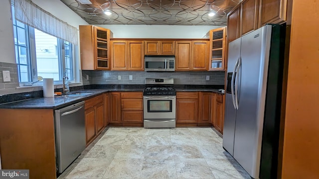 kitchen featuring backsplash, stainless steel appliances, dark stone countertops, and sink