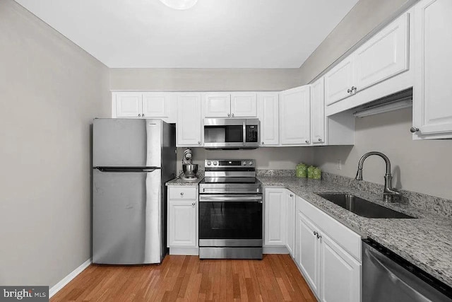 kitchen with white cabinets, light wood-type flooring, appliances with stainless steel finishes, and sink