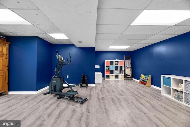 workout room featuring a paneled ceiling and light hardwood / wood-style floors