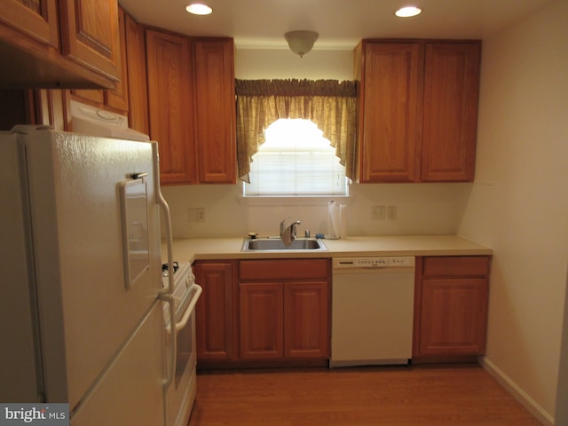 kitchen with sink, white appliances, and hardwood / wood-style flooring