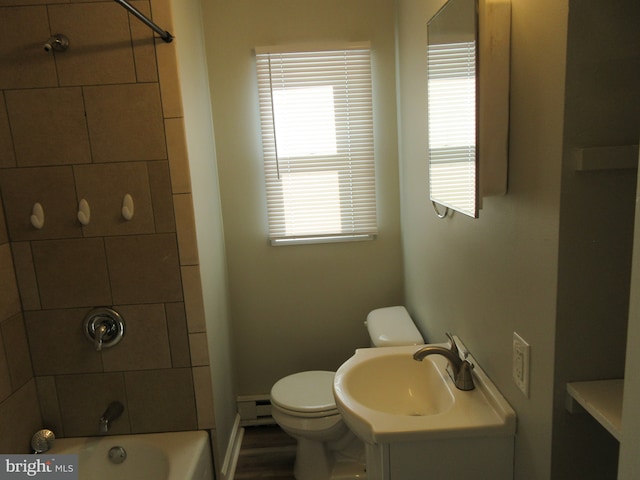 full bathroom featuring vanity, toilet, baseboard heating, and tiled shower / bath combo