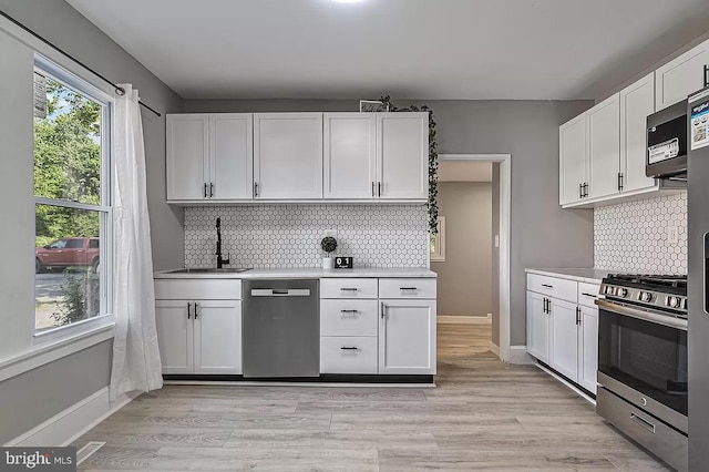 kitchen featuring white cabinetry, sink, stainless steel appliances, and light hardwood / wood-style floors