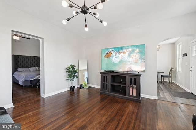 living room with ceiling fan with notable chandelier and dark wood-type flooring