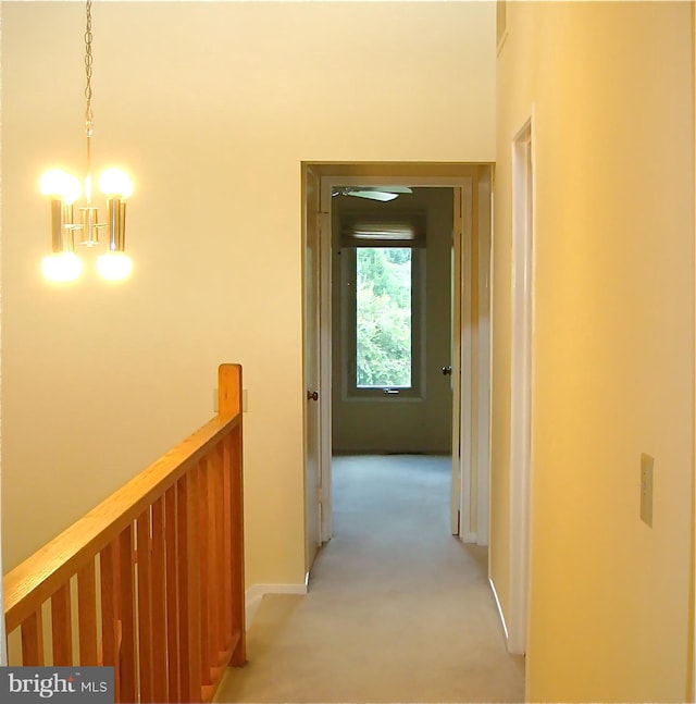 corridor with light colored carpet and an inviting chandelier