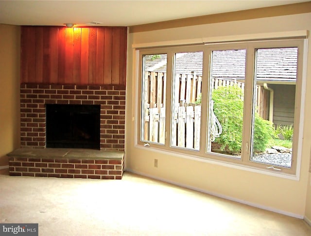 unfurnished living room featuring carpet floors and a brick fireplace