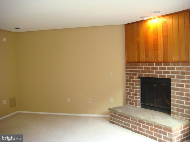 unfurnished living room with carpet flooring and a brick fireplace