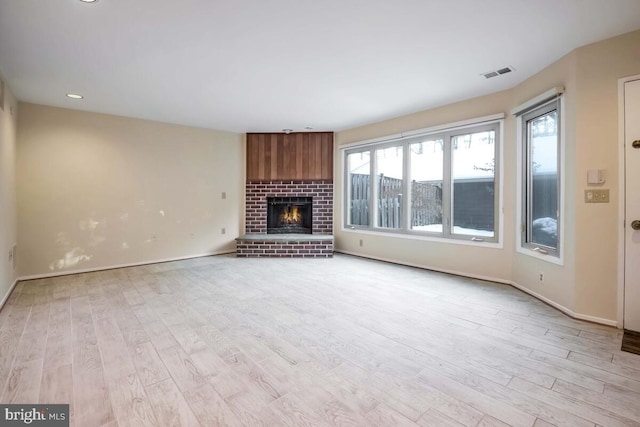 unfurnished living room with a fireplace, a wealth of natural light, and light hardwood / wood-style flooring