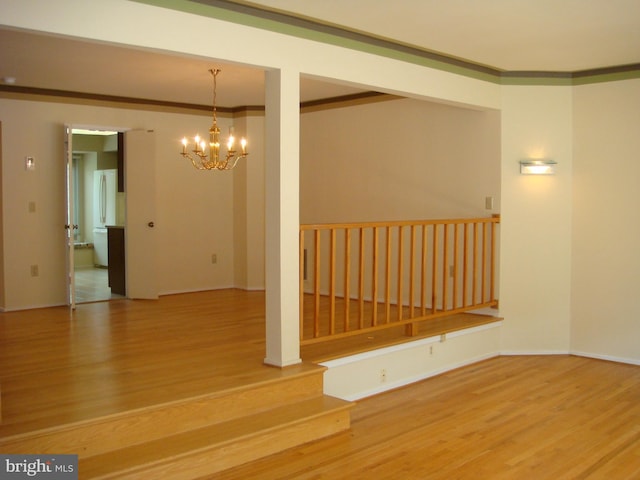 empty room with an inviting chandelier, ornamental molding, and hardwood / wood-style flooring