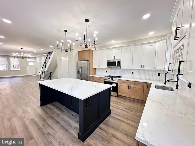 kitchen featuring light stone countertops, appliances with stainless steel finishes, a center island, and decorative light fixtures