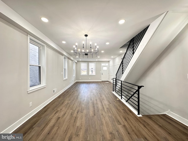 unfurnished living room with dark wood-type flooring and an inviting chandelier