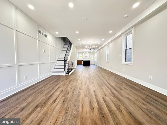 unfurnished living room featuring a chandelier and hardwood / wood-style floors