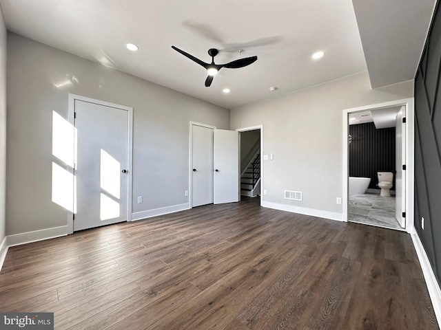 unfurnished bedroom with ensuite bath, ceiling fan, and dark wood-type flooring