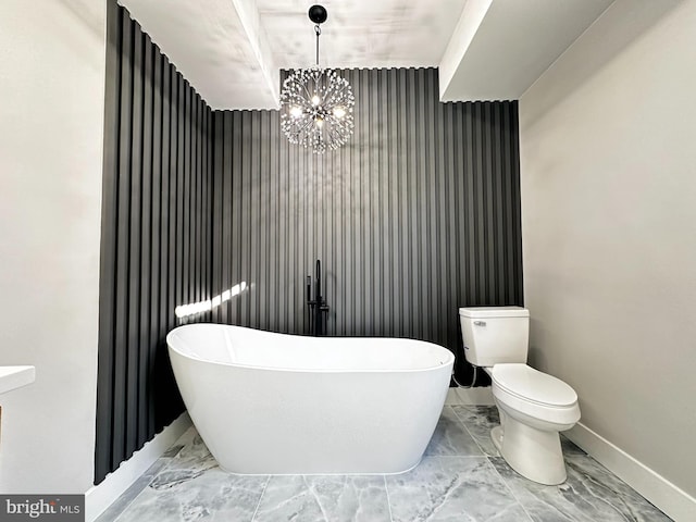 bathroom with a bathing tub, toilet, and a notable chandelier