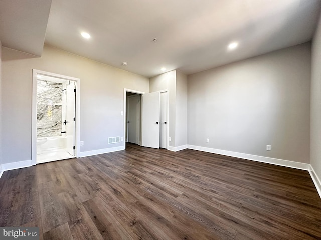 unfurnished bedroom featuring connected bathroom and dark hardwood / wood-style floors