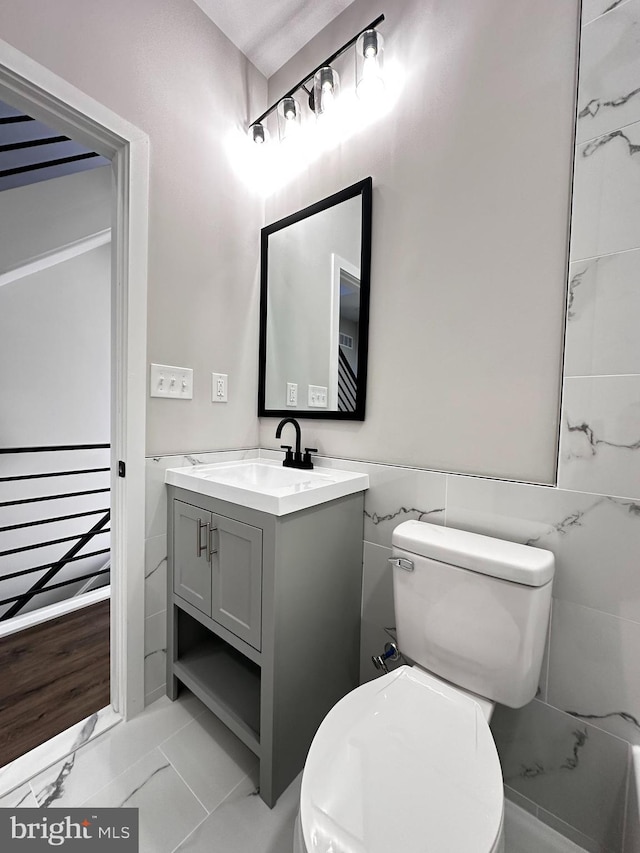 bathroom featuring tile patterned floors, vanity, toilet, and tile walls