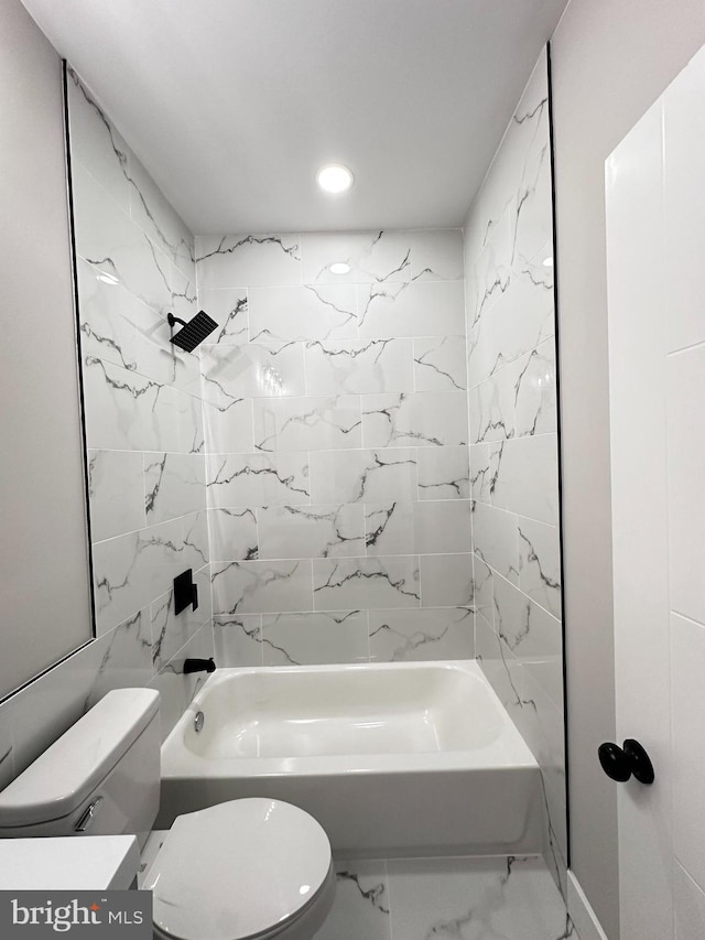 bathroom featuring tiled shower / bath combo and toilet