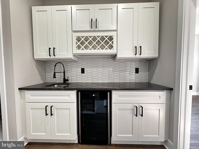 bar with tasteful backsplash, beverage cooler, sink, white cabinets, and dark hardwood / wood-style floors