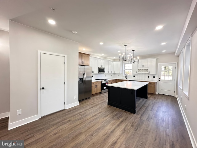 kitchen featuring dark hardwood / wood-style flooring, stainless steel appliances, pendant lighting, white cabinetry, and a kitchen island