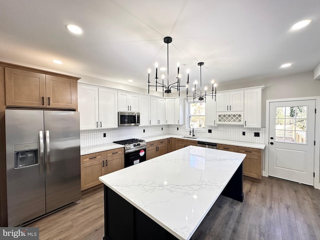 kitchen featuring a center island, sink, stainless steel appliances, pendant lighting, and white cabinets