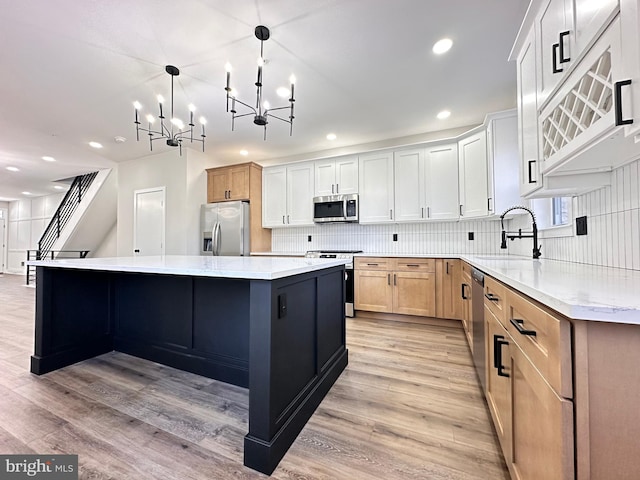 kitchen with hanging light fixtures, an inviting chandelier, a spacious island, white cabinets, and appliances with stainless steel finishes