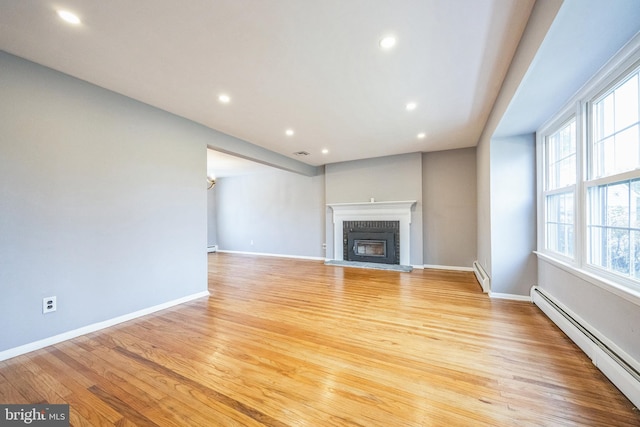 unfurnished living room with a fireplace, light hardwood / wood-style floors, and baseboard heating