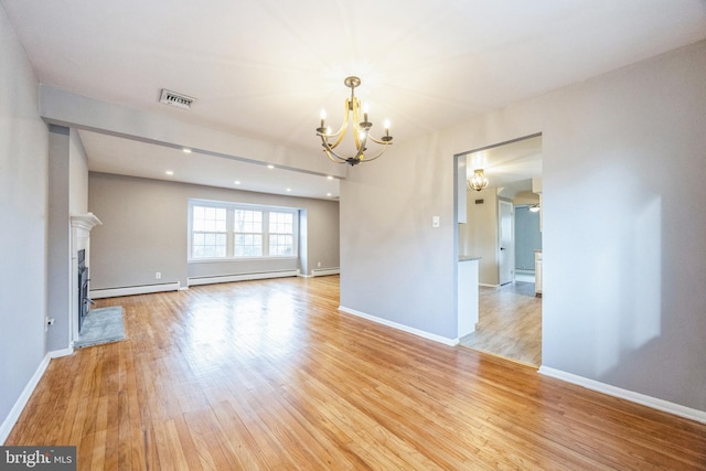 unfurnished living room with ceiling fan with notable chandelier, light hardwood / wood-style floors, and a baseboard heating unit