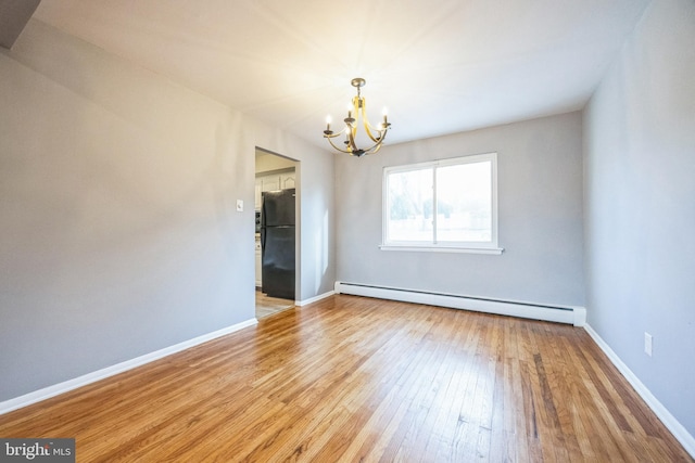 unfurnished room featuring a chandelier, baseboard heating, and light hardwood / wood-style flooring