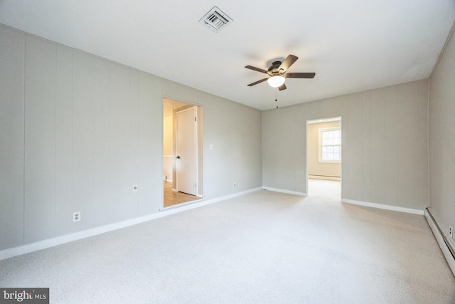 empty room with light colored carpet, baseboard heating, and ceiling fan