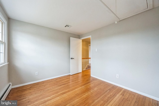 spare room featuring a baseboard radiator and light hardwood / wood-style floors