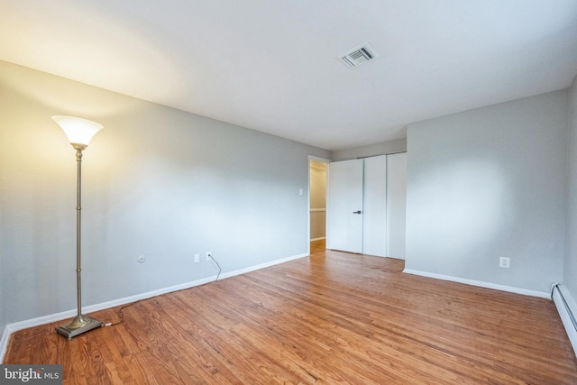 spare room featuring hardwood / wood-style floors and a baseboard heating unit