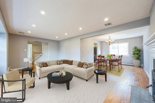 living room with light hardwood / wood-style floors, baseboard heating, and a chandelier