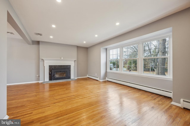 unfurnished living room with a brick fireplace, a baseboard radiator, and light hardwood / wood-style floors