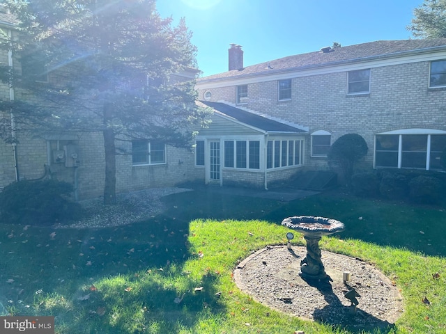 back of property with a sunroom, a yard, and a patio