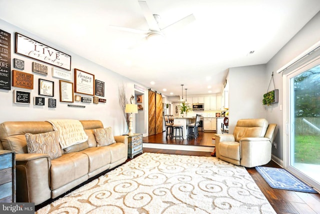 living room featuring hardwood / wood-style flooring, ceiling fan, and a barn door